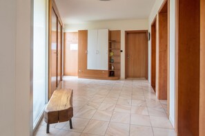 Un pasillo con un banco de madera, un armario y una estantería.