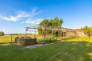 A greenhouse structure with a metal frame and wooden beams, surrounded by a well-maintained lawn and a metal fence. - Villa Prleski Raj - Pool, Sauna, Jacuzzi (Križevci)