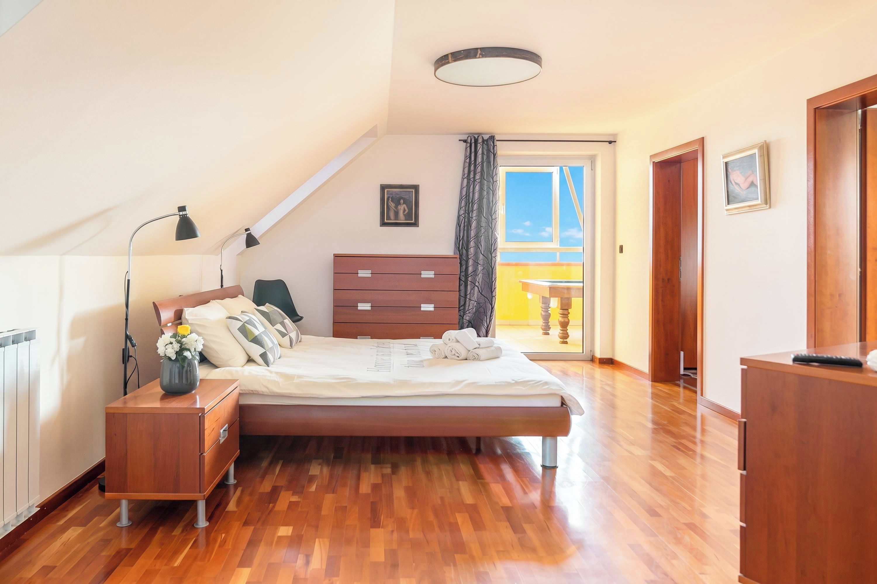 Un dormitorio con cama, mesita de noche, cómoda y vistas al exterior.