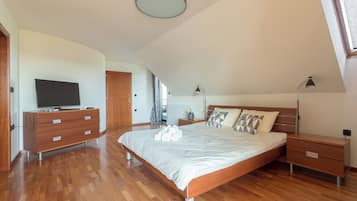 Un dormitorio con una cama, un tocador, una mesita de noche, una lámpara y un televisor.