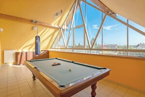 A pool table in a room with yellow walls, a large window, and a punching bag.