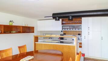 Una cocina moderna con una isla central, sillas de madera, una mesa de comedor y armarios empotrados.