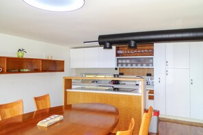 A modern kitchen with a central island, wooden chairs, a dining table, and built-in cabinets. - Villa Prleski Raj - Pool, Sauna, Jacuzzi (Križevci)