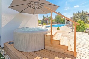 A hot tub on a wooden deck with a pool in the background. - Villa Prleski Raj - Pool, Sauna, Jacuzzi (Križevci)