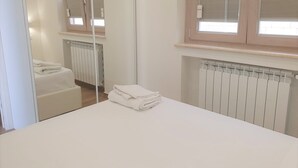 A hotel room with a bed, a radiator, and a window with blinds. - Appartamenti Borgo Panoramico N.8 (Tropea)
