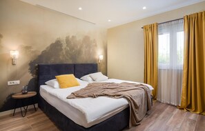 Une chambre à coucher comprenant un lit, deux lampes de chevet, une table de chevet, une fenêtre avec des rideaux et un mur au motif texturé.
