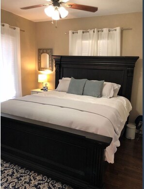 Relax in a serene space with a large bed, bedside table, and ceiling fan.
