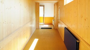 A wooden interior hallway with a door at the end, a radiator on the right, and a window on the left. - A large chalet for getting together with family, friends or colleagues!  (Cerniat)
