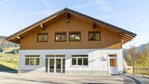 A two-story wooden building with a sloped roof, large windows, and a white facade.