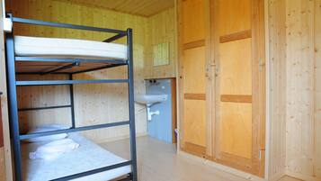 Ein Stockbett mit Waschbecken und einem Holzschrank in einem Zimmer mit Holzwänden.