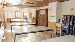 A classroom with tables and chairs, a wooden door, a whiteboard, and a vending machine. - A large chalet for getting together with family, friends or colleagues!  (Cerniat)