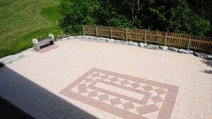 A paved outdoor area with a geometric pattern, a wooden fence, and a bench. - A large chalet for getting together with family, friends or colleagues!  (Cerniat)
