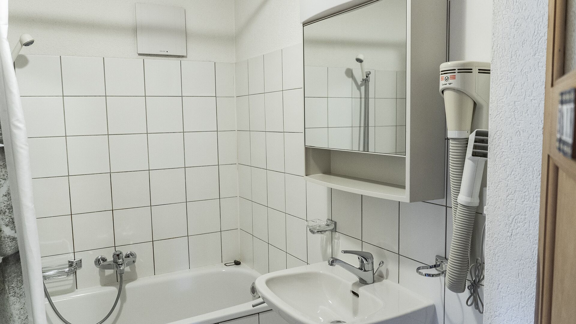 Een badkamer met een bad, wastafel, spiegel en haardroger.
