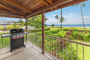 Ein überdachter Außenbereich mit Grill und Blick auf Strand und Meer.