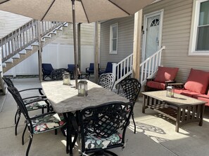 Un patio con una mesa y sillas, un sofá y una escalera que lleva a una casa.