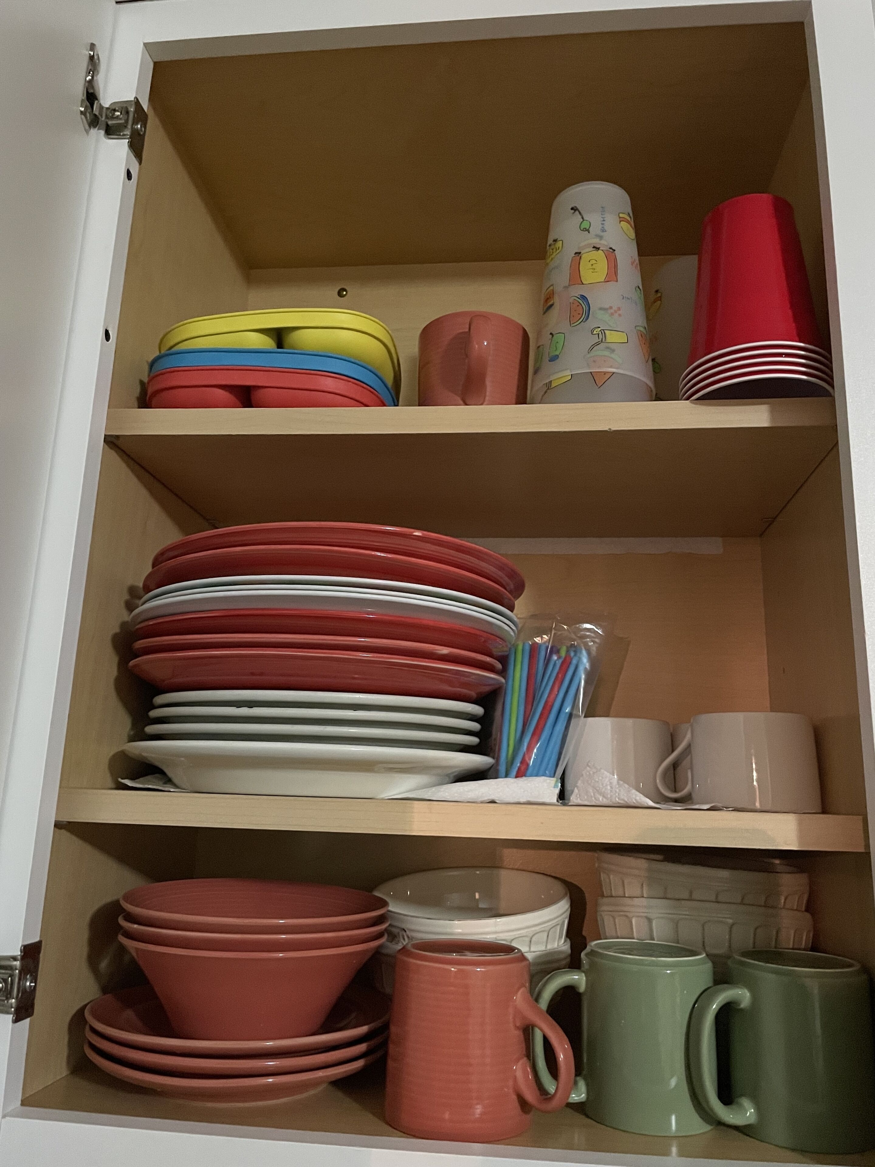 Ein Schrank mit mehreren Regalen, der verschiedene Küchenutensilien wie Teller, Schüsseln und Tassen beherbergt.