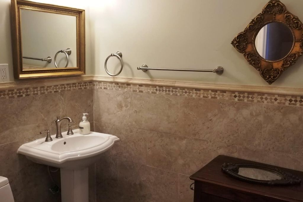 Une salle de bain avec un lavabo sur colonne, un porte-serviettes, des toilettes et un miroir décoratif.