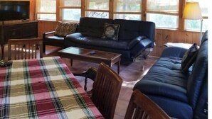 A cozy cabin interior with a wooden interior, a sofa, a plaid tablecloth, and a television. - NEW VICTORIAN GEM IN GREENPORT (Greenport)