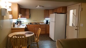 A compact kitchen with wooden cabinets, a refrigerator, a stove, and a dining table with chairs. - Property near Pioneer Park, Chena River, and the Carlson Center. Sleeps 4 (Fairbanks)