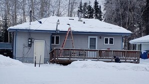 A single-story house with a covered porch, a ladder leaning against the house, and a snow-covered roof. - Property near Pioneer Park, Chena River, and the Carlson Center. Sleeps 4 (Fairbanks)