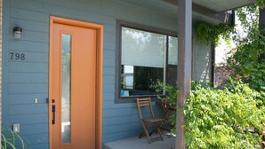 Una casa con fachada azul, el número '798' en la pared, una puerta de madera y una ventana con vista al cielo.