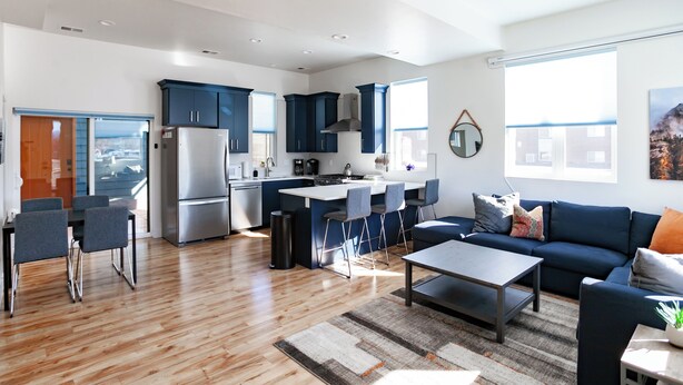 Una cocina moderna con armarios azul oscuro, un refrigerador de acero inoxidable y una isla central con taburetes de bar.