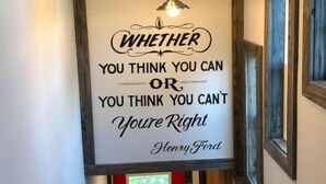Ein Flur mit einem motivierenden Zitat an der Wand, einer roten Tür und einer Pendelleuchte.