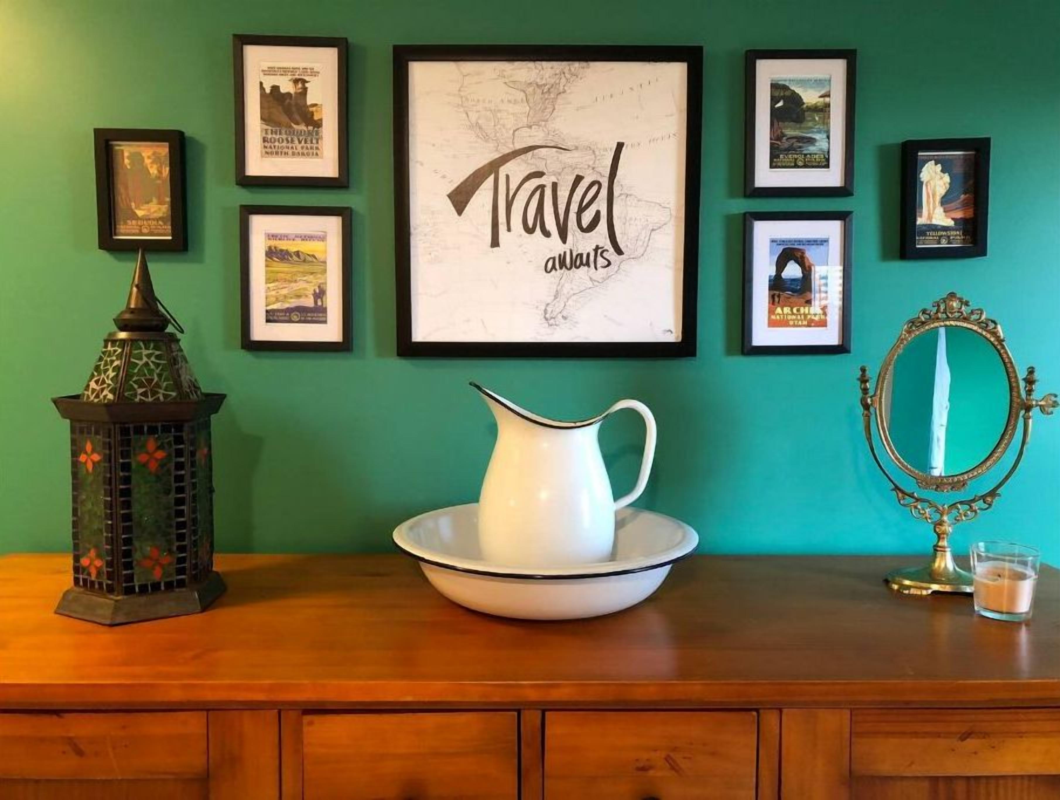 Un aparador de madera con una jarra blanca sobre un platón, un farol decorativo y un mapa enmarcado con el texto 