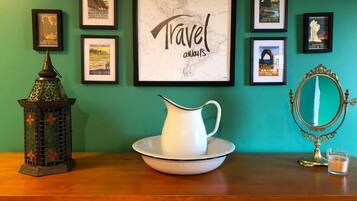 Un aparador de madera con una jarra blanca sobre un platón, un farol decorativo y un mapa enmarcado con el texto
