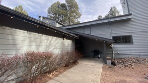 A house with a covered porch, a concrete pathway, and a string of lights. - Historic Firehouse - Spacious, Private & Clean (Kachina Village)