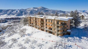 Un hôtel à plusieurs étages, dont la façade est recouverte de neige, situé dans une région montagneuse sous un ciel dégagé.