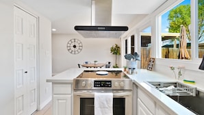 A modern kitchen with a stainless steel stove, oven, and a large window. - Renovated Townhome near Oldtown Scottsdale (Large Patio and Community Pool) (Scottsdale)