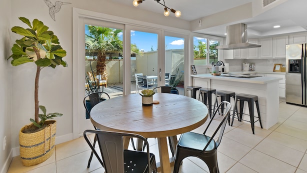 A modern kitchen with white cabinets, a central island with stools, and a hanging light fixture. - Renovated Townhome near Oldtown Scottsdale (Large Patio and Community Pool) (Scottsdale)
