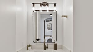 A bathroom with a white vanity, dark cabinet, and a mirror with lights above. - Renovated Townhome near Oldtown Scottsdale (Large Patio and Community Pool) (Scottsdale)