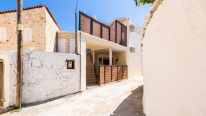 A narrow street with a building featuring a stone facade, a wooden fence, and a staircase leading to an upper level. - Maria's Place, a great place to experience Crete! (Rethymno)