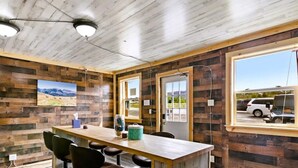 Una habitación con paneles de madera, una ventana grande, una mesa, sillas y una puerta.