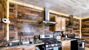 Una cocina rústica con paredes de madera, estufa de acero inoxidable y armarios de madera.