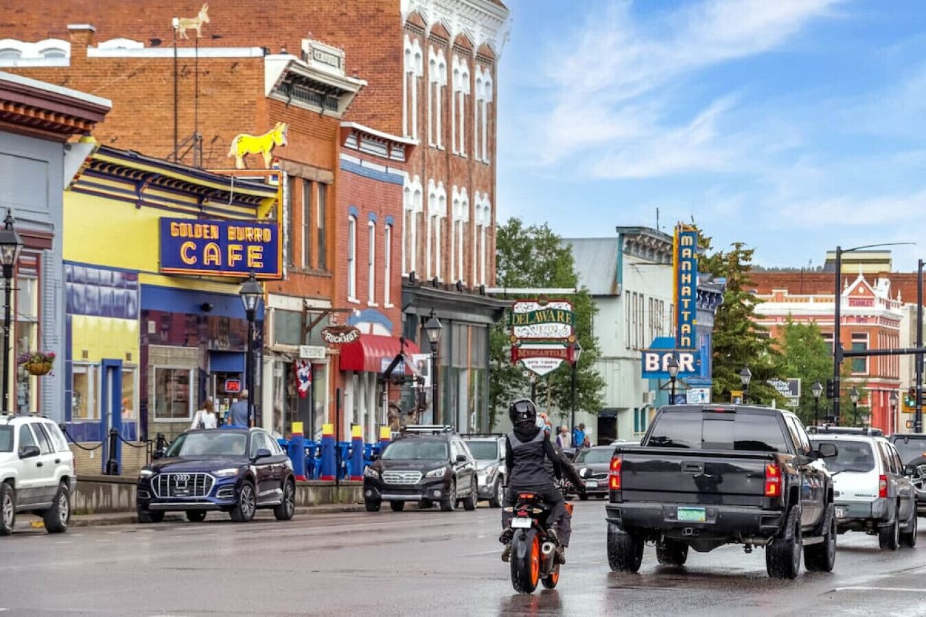 Gadescene med en café, et skilt med Delaware og en mand på en motorcykel.