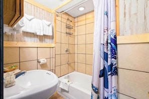 Ein Badezimmer mit Waschbecken, Badewanne, Dusche und Holzvertäfelung.