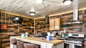 Una cocina rústica con paredes de madera, una barra y electrodomésticos modernos.