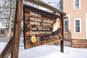 Ein Holzschild empfängt Besucher im historischen Bergbauland Colorado, zeigt einen Bergschafthelm und informiert über den Schutz von Colorados historischem Erbe.