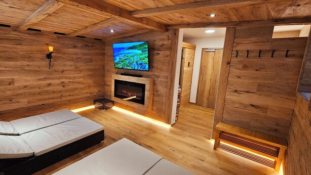 Une pièce chaleureuse avec des murs en bois, un lit, une cheminée et un téléviseur fixé au mur.