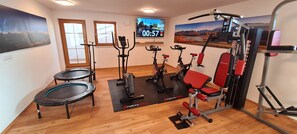 A gym with exercise equipment, a TV, and large windows.