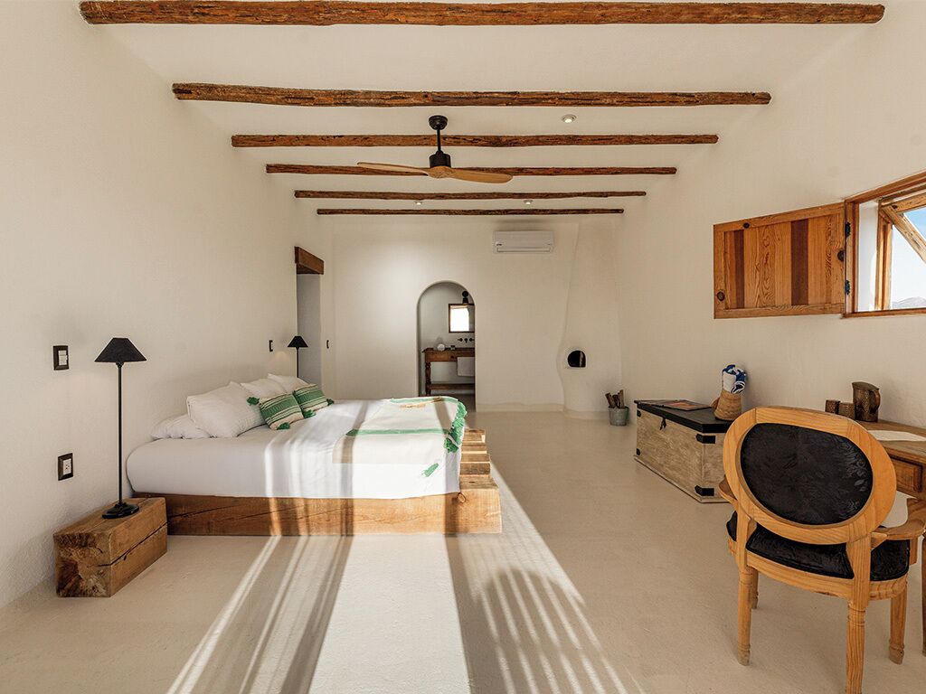 Un dormitorio con cama, mesita de noche, lámpara, silla de madera y un escritorio con silla.