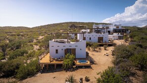 A desert resort with multiple white buildings, a wooden deck, and a swimming pool. - NEST Baja, Member of Design Hotels (La Fortuna)