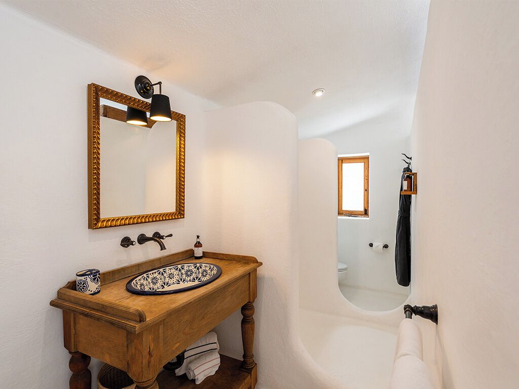 A bathroom with a wooden vanity, a large mirror, and a bathtub.