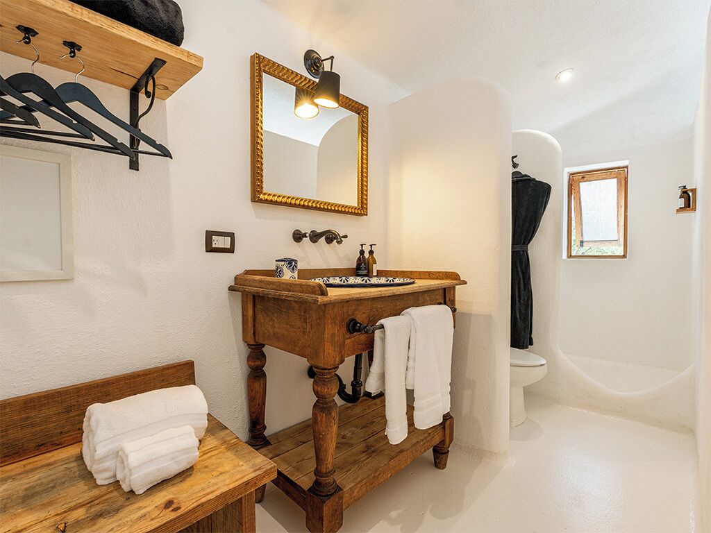A bathroom with a wooden vanity, a large mirror, a sink, and a toilet.