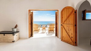 A room with a large wooden door leading to a balcony with beach chairs and a view of the sea. - NEST Baja, Member of Design Hotels (La Fortuna)