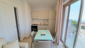 A compact living space with a kitchenette, a dining area, and a balcony with a view. - Appartamenti Borgo Panoramico N.9 (Tropea)