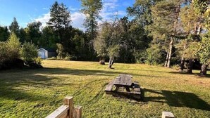 A wooden deck leading to a grassy yard with a picnic table and a shed in the background. - Beautiful Renovated Home Walk to University of Maine in Orono (Orono)